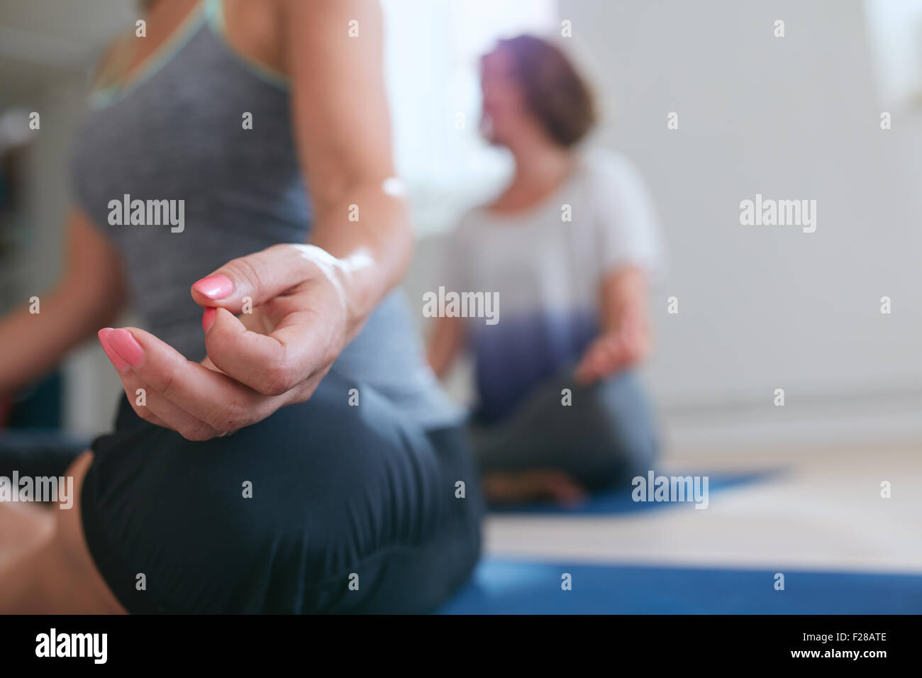 Frau sitzt mit ihren Beinen gekreuzt und hand ruht auf Knie. Nahaufnahme von Frauenhand während der Yoga-Stunde zu meditieren. Lotus-pose Stockfoto