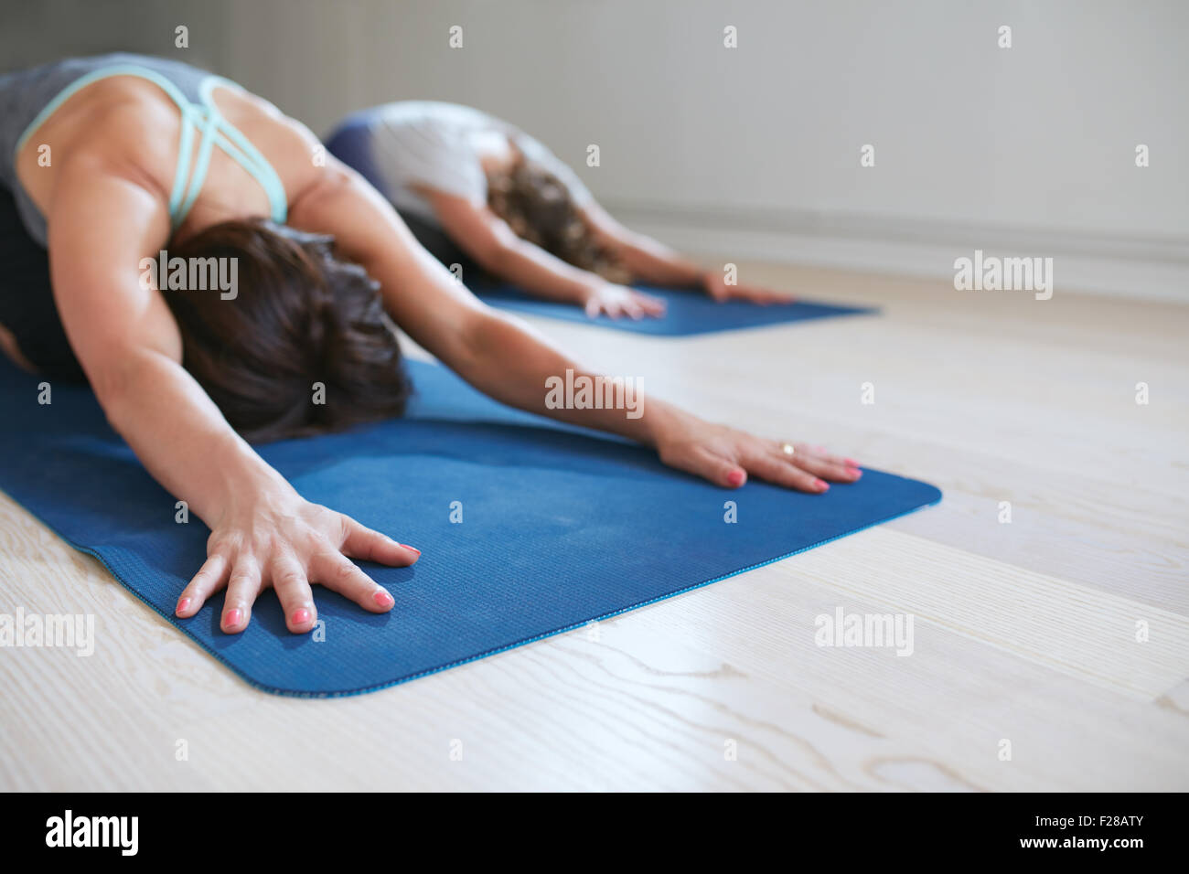 Zwei Frauen dabei stretching Training im Fitness-Matte. Weibchen, die Durchführung von Yoga auf Übung Matte im Fitnessstudio. Kind-Pose, Balasana. Stockfoto