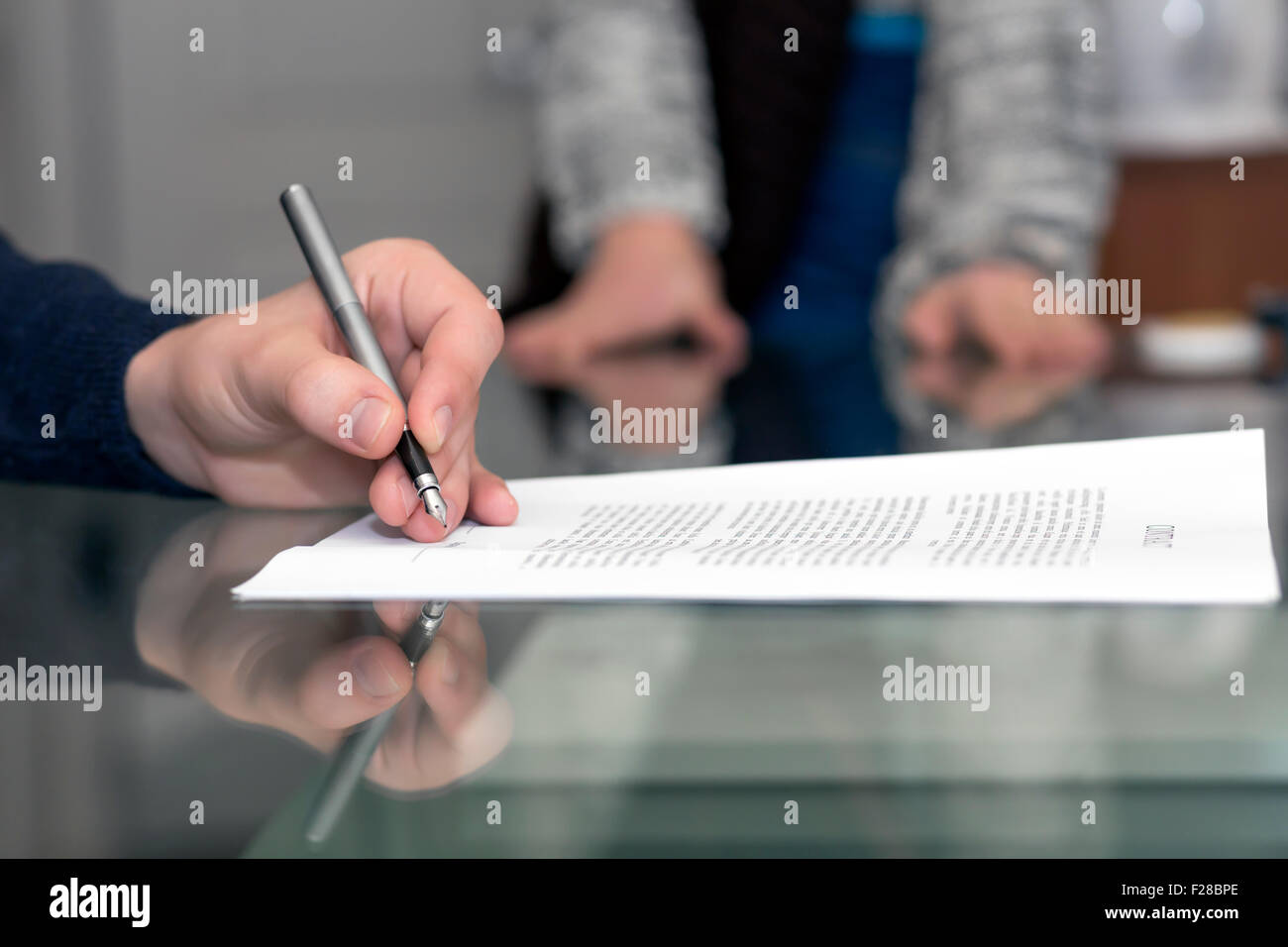 Händen eines Mannes signieren formale Papier und weibliche Hände im Hintergrund Stockfoto