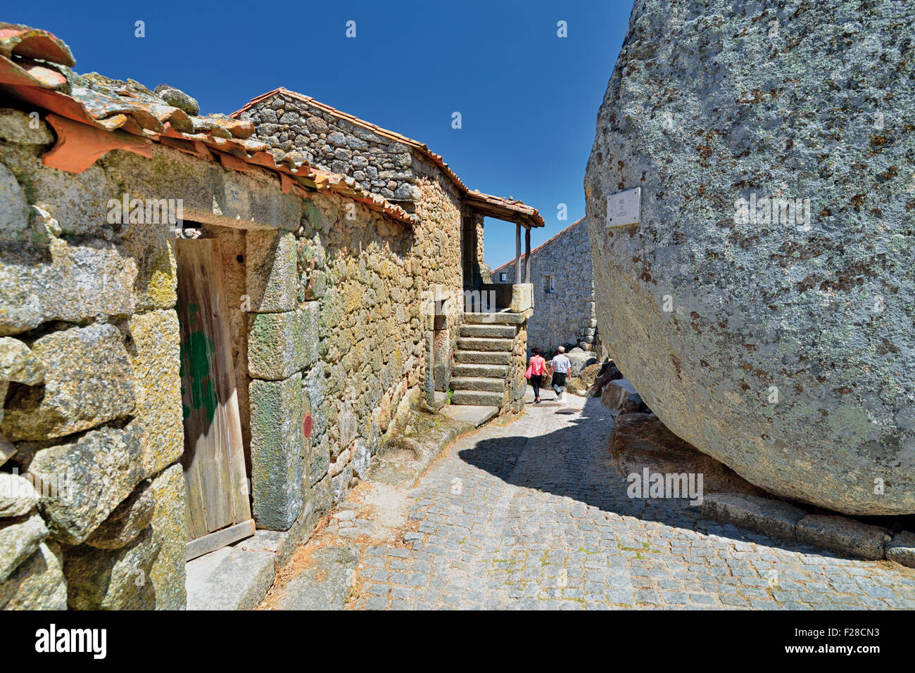 Portugal: Touristen zu Fuß in einer Gasse mit rustikalen Steinhäusern und riesige Granitfelsen in Monsanto Stockfoto