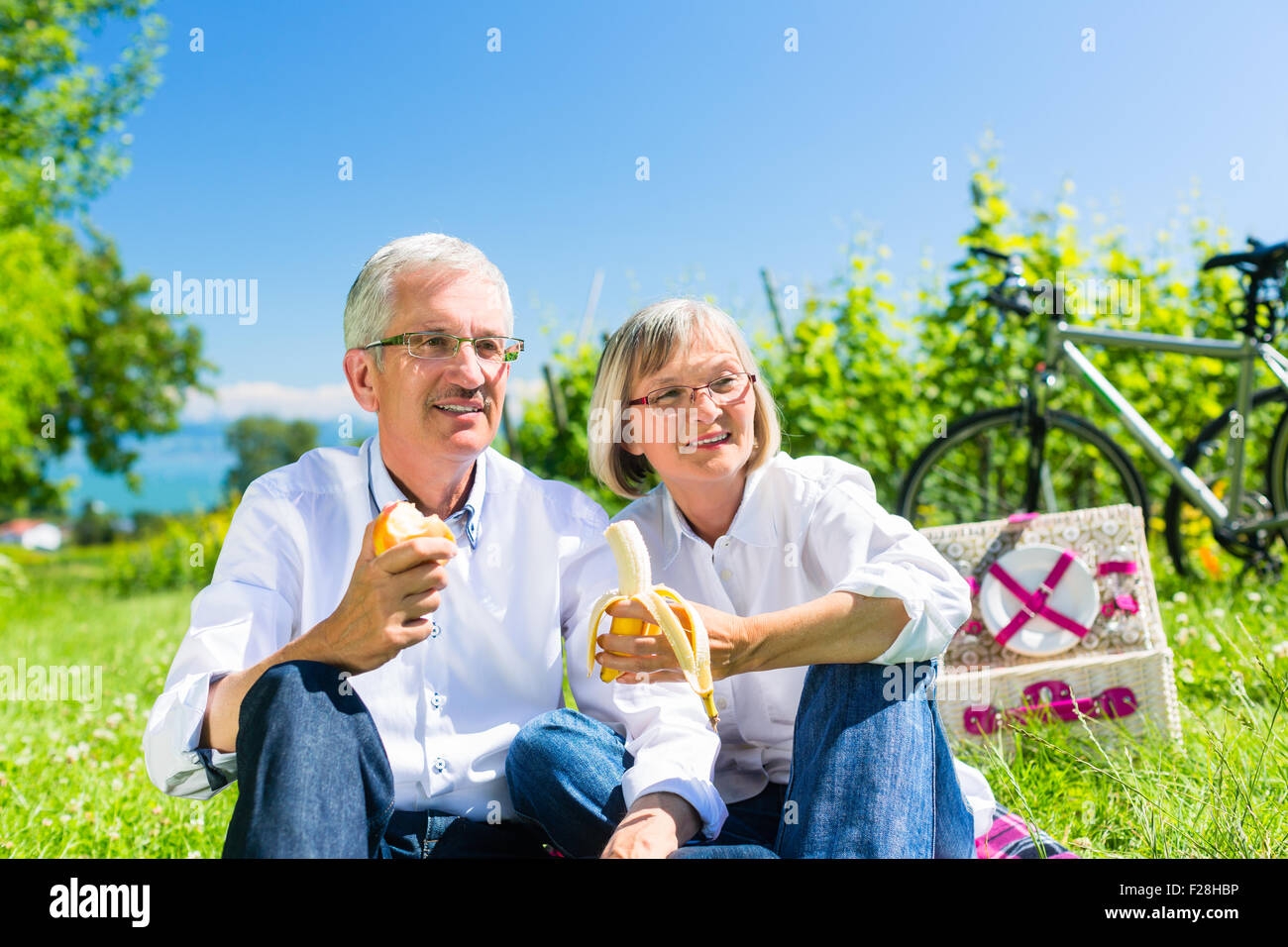 Älteres paar Obst essen und trinken am Picknick im Sommer, wunderschöne Landschaft im Hintergrund Stockfoto