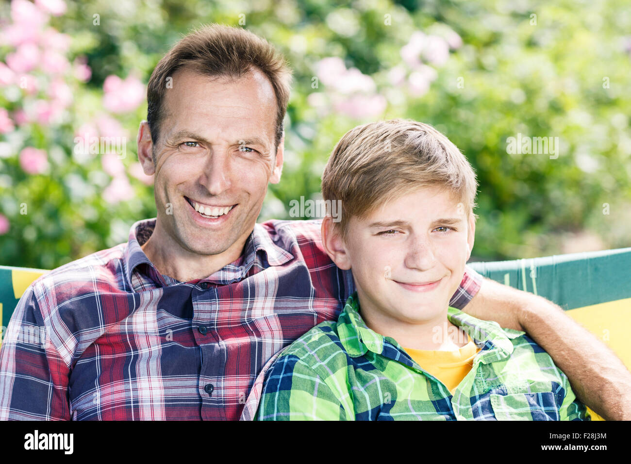 Vater und Sohn umarmt, sitzen im park Stockfoto