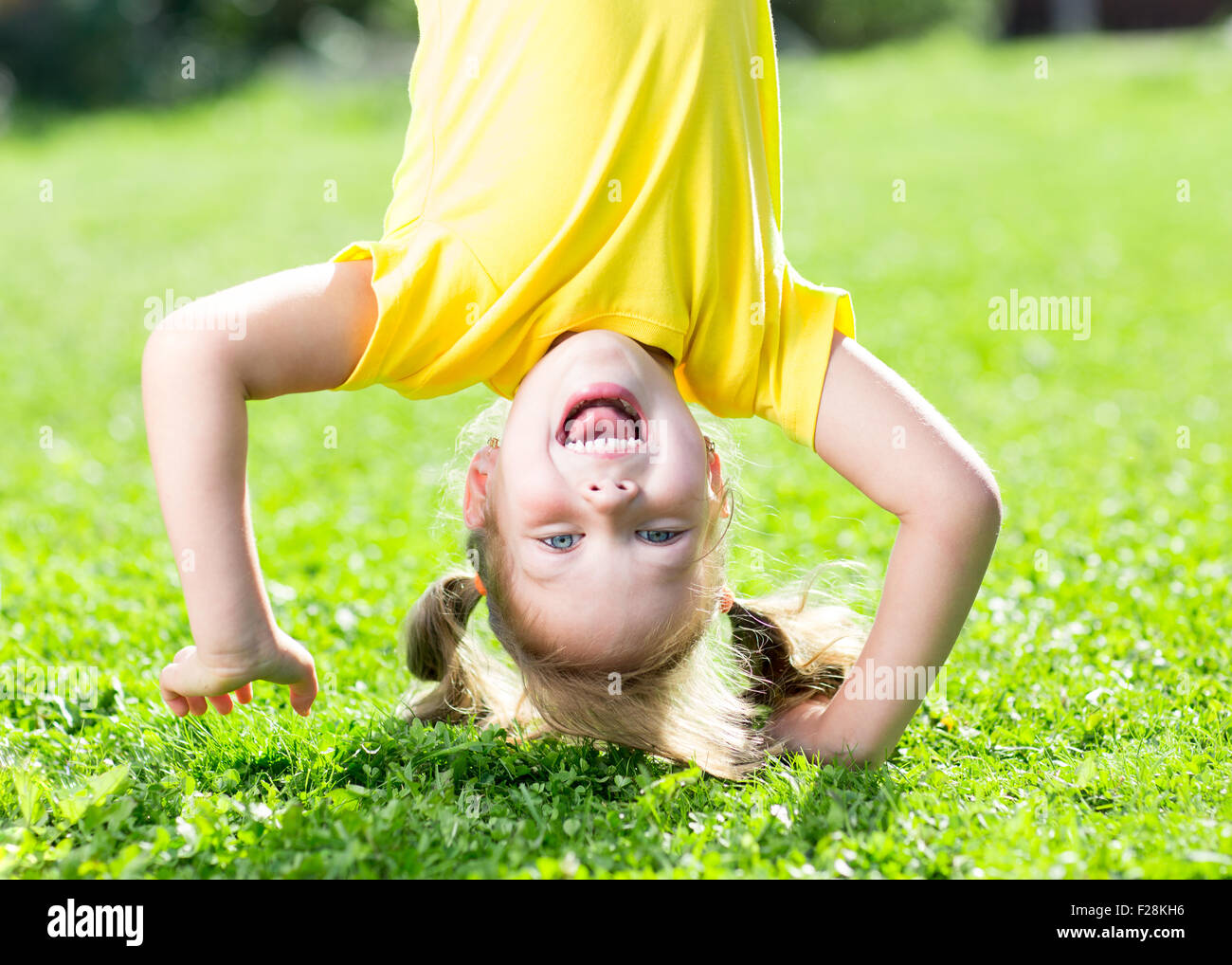 Kind Mädchen steht auf dem Kopf stehend auf dem Kopf auf dem Rasen im Sommer Stockfoto