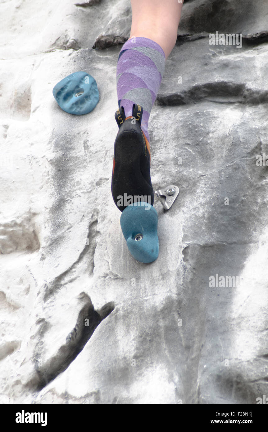 Junges Teen Mädchen klettert auf eine künstliche Kletterwand Nahaufnahme von den Füßen und spezielle Kletterschuhe Stockfoto