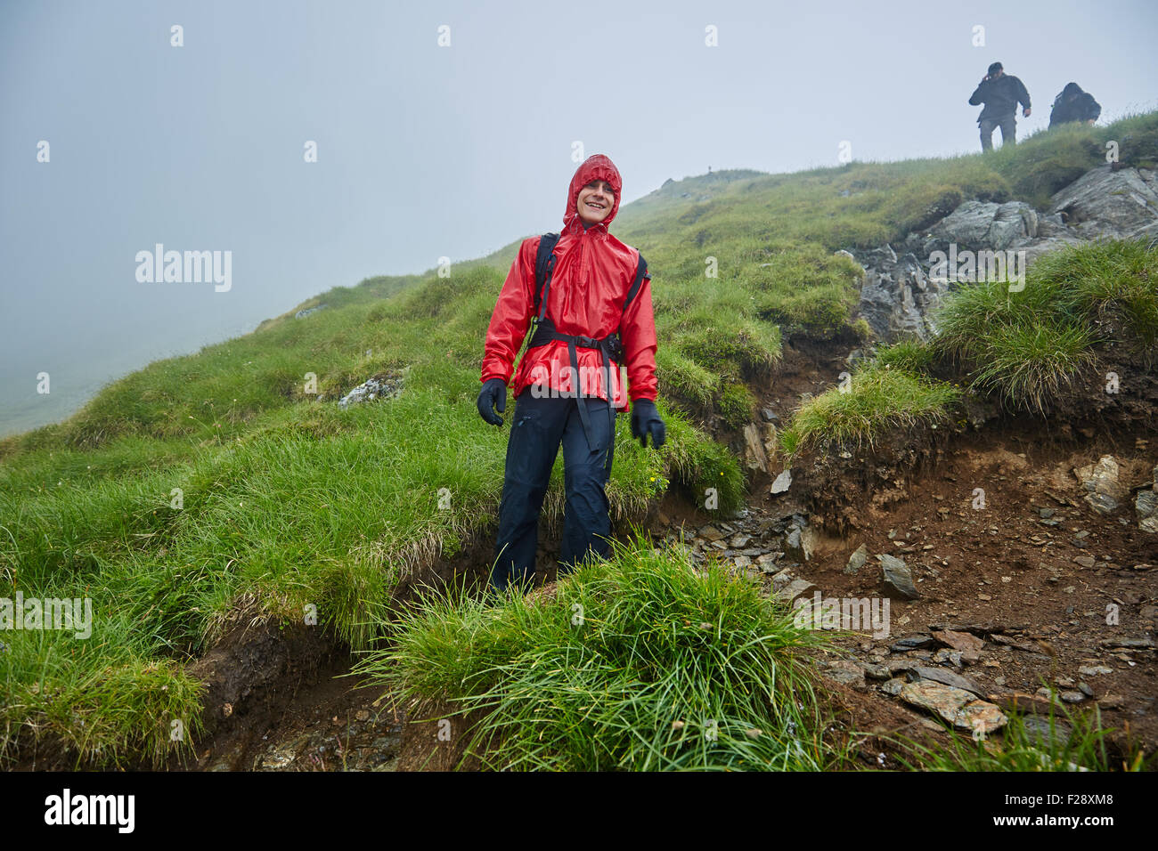 Gruppe von Wanderern absteigend auf einem Berg mit Regenschutz bei Regen Stockfoto