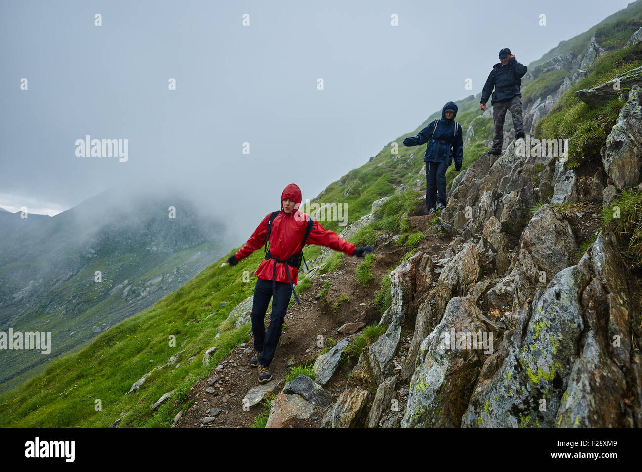 Gruppe von Wanderern absteigend auf einem Berg mit Regenschutz bei Regen Stockfoto