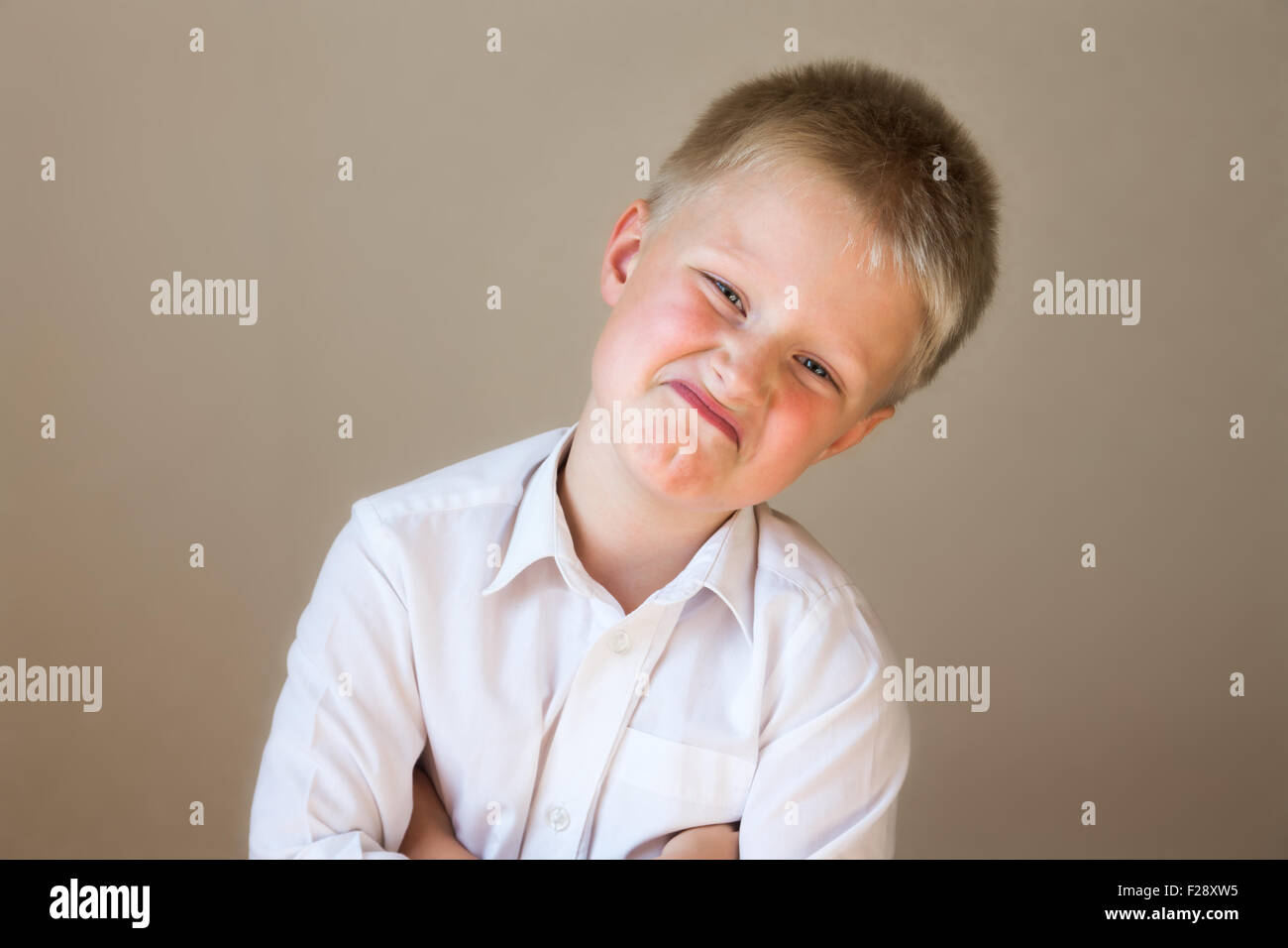 Arrogante ungläubig lustig Kind (junge) posiert in weißen Hemd über grauen Hintergrund Stockfoto