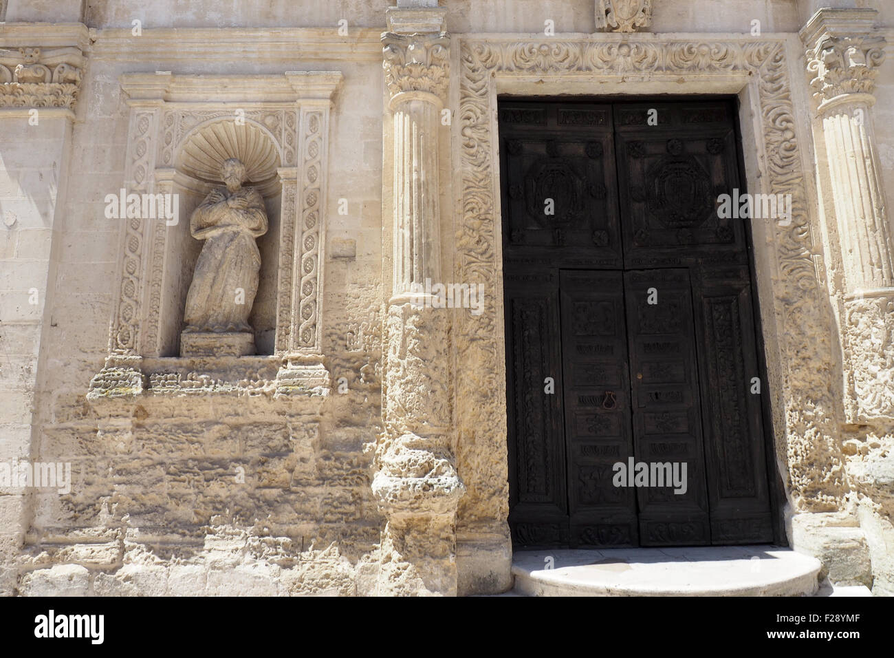 Holztür, Statue und dekorative Sandsteinfassade der Kirche Santa Chiara, Matera. Stockfoto