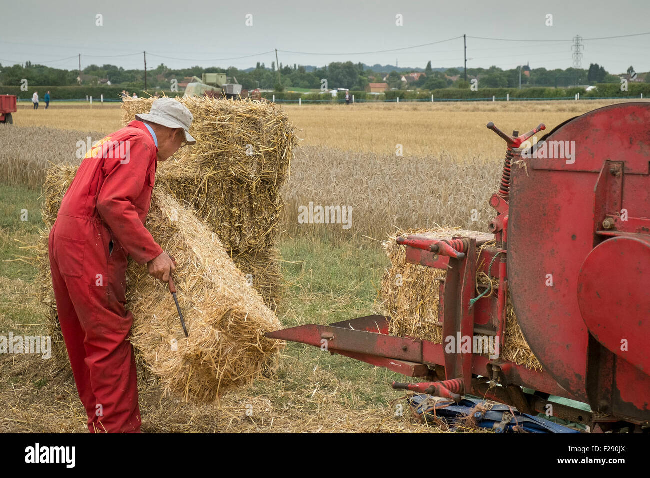 Ein Landarbeiter Stapeln von Ballen mit einem Oldtimer pressen Maschine an der Essex Land zeigen, Barleylands, Essex produziert. Stockfoto