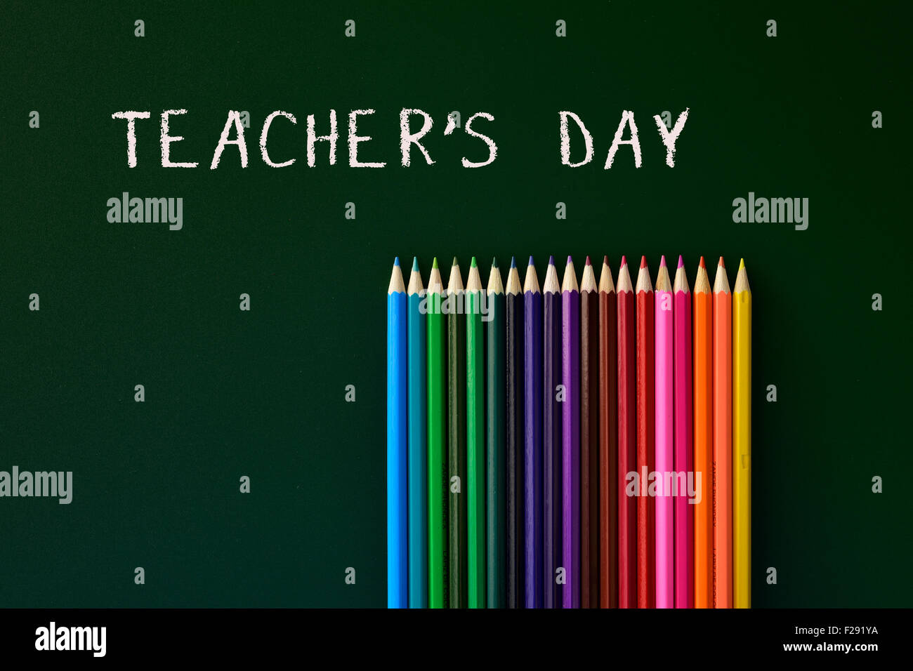 einige farbige Stifte in verschiedenen Farben und die Text-Lehrer-Tag in eine grüne Tafel geschrieben Stockfoto