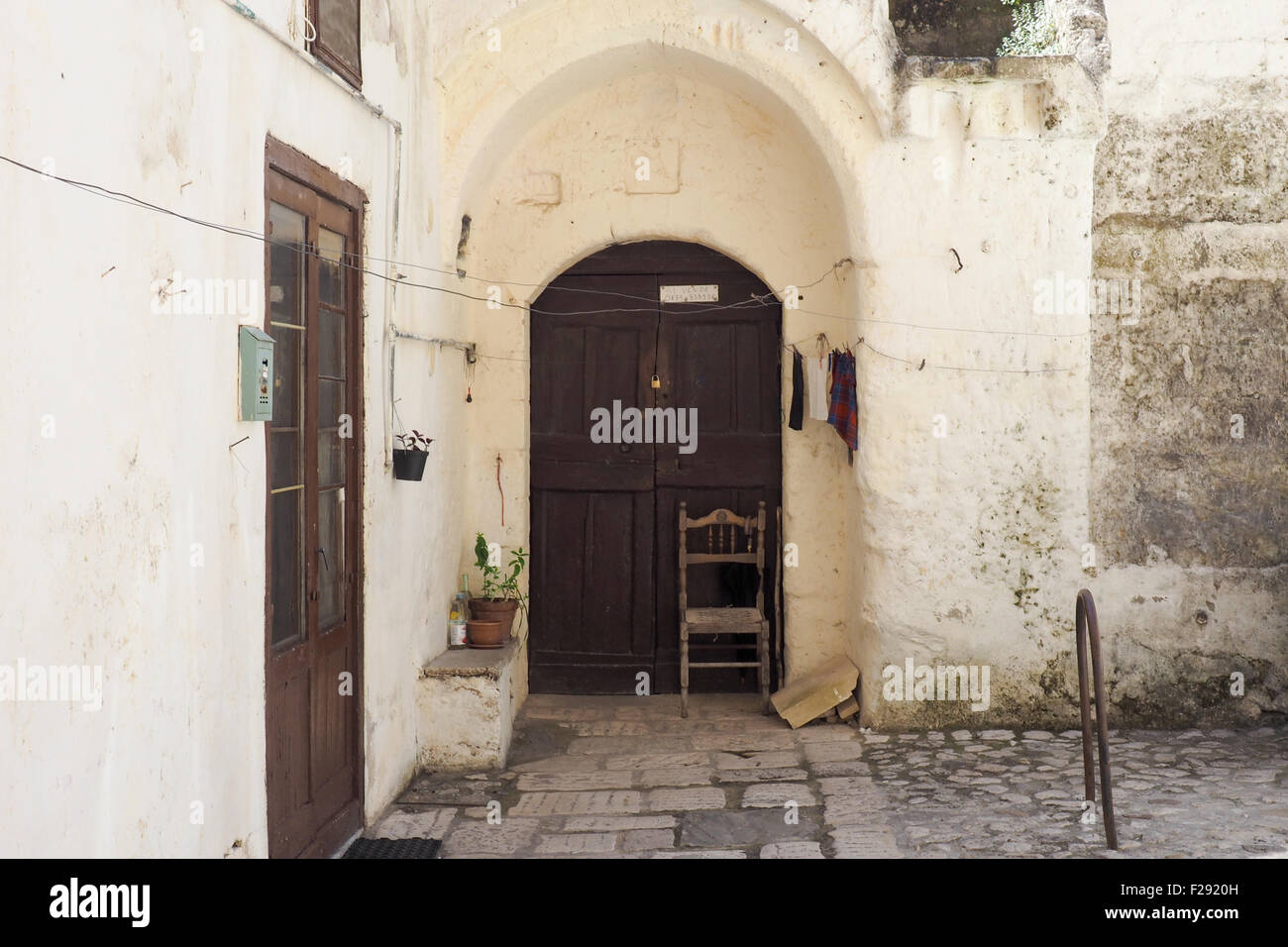 Ein Holzstuhl vor einer hölzernen Tür in einem Innenhof. Stockfoto