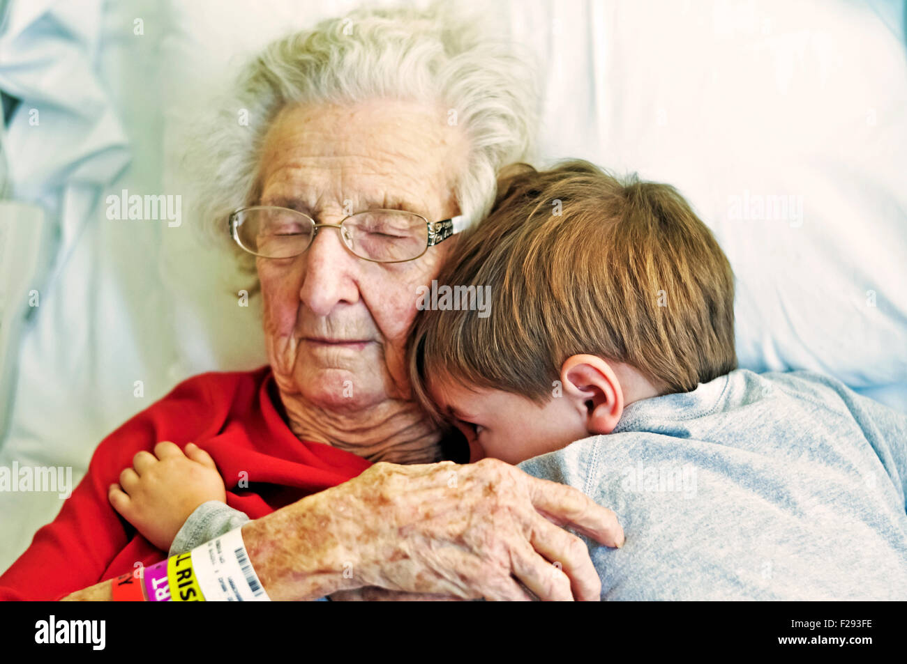 Ältere Dame und Enkel hug im Krankenhausbett Stockfoto