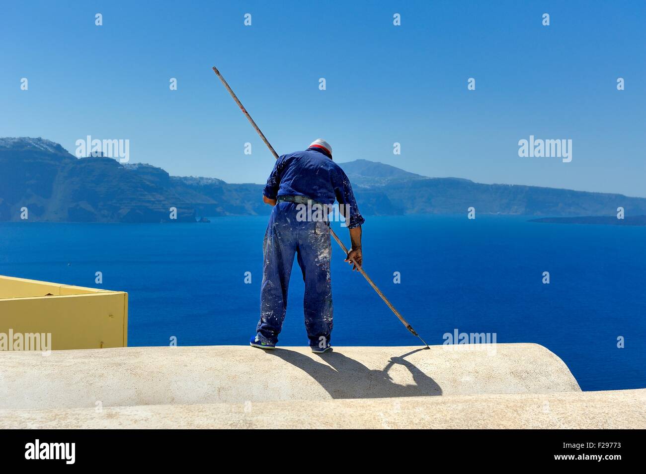 Ein Mann arbeitet auf einem Hoteldach auf die Caldera, Santorini, Griechenland Stockfoto