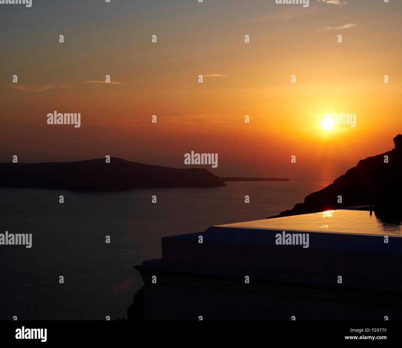 Sonnenuntergang beleuchtet ein Schwimmbad auf der Caldera, Santorini, Griechenland Stockfoto