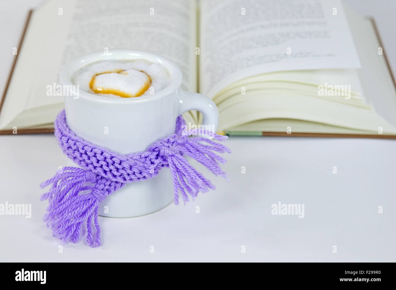 Lila Winter stricken Schal umwickelt mit Herz und Buch auf weiß Cappuccino trinken. Stockfoto