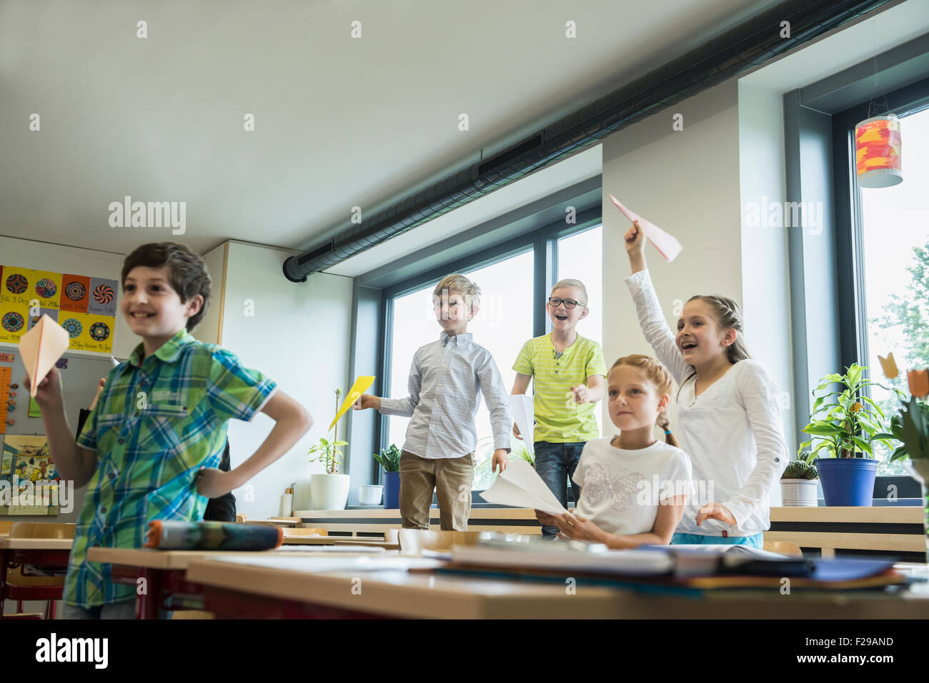 Schulkinder spielen mit Papierflugzeugen im Klassenzimmer, München, Bayern, Deutschland Stockfoto