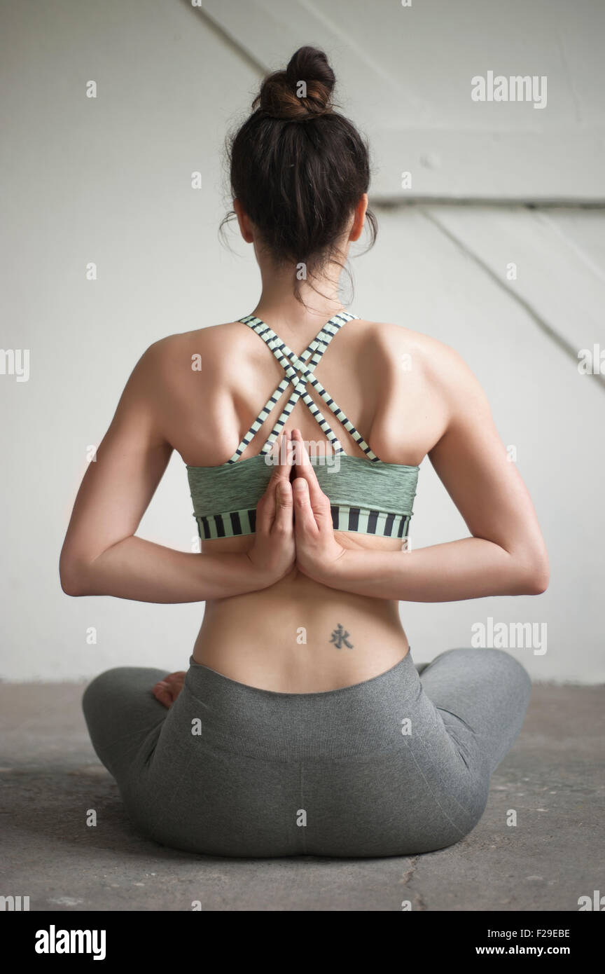 Rückansicht einer Mitte erwachsenen Frau tun Pashchima Namaskarasana Position im Yoga-Studio, München, Bayern, Deutschland Stockfoto