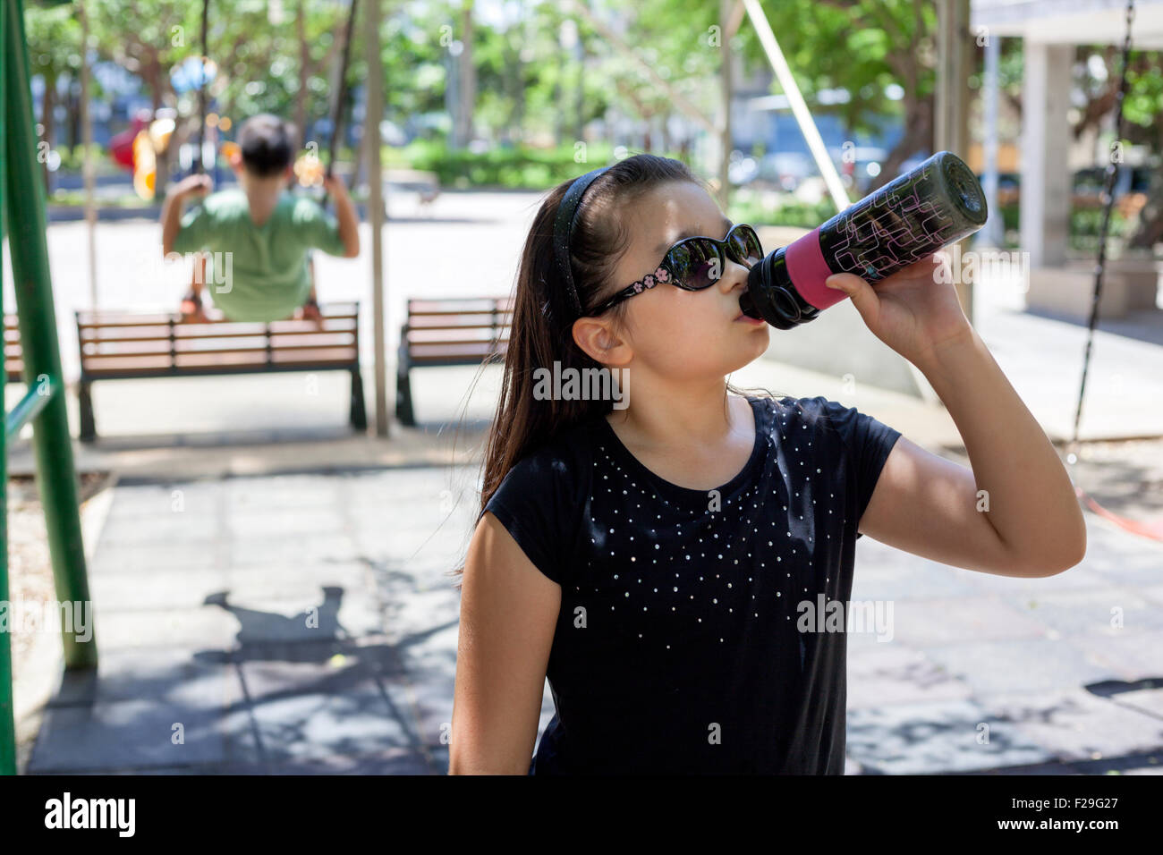 junge Mischlinge Mädchen trinken zum Abkühlen im park Stockfoto