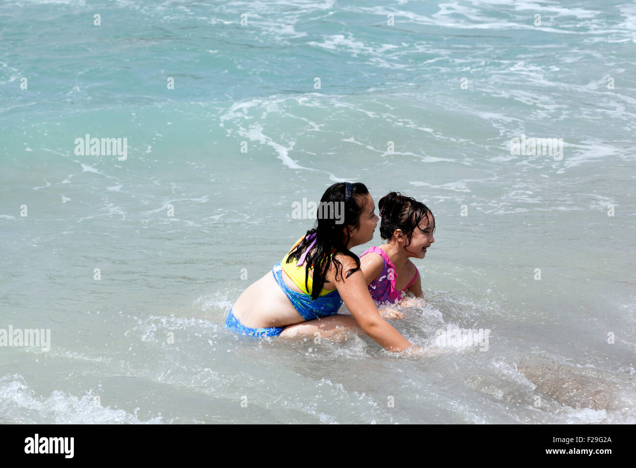 zwei junge Mädchen gemischter Herkunft spielen im Ozean Stockfoto
