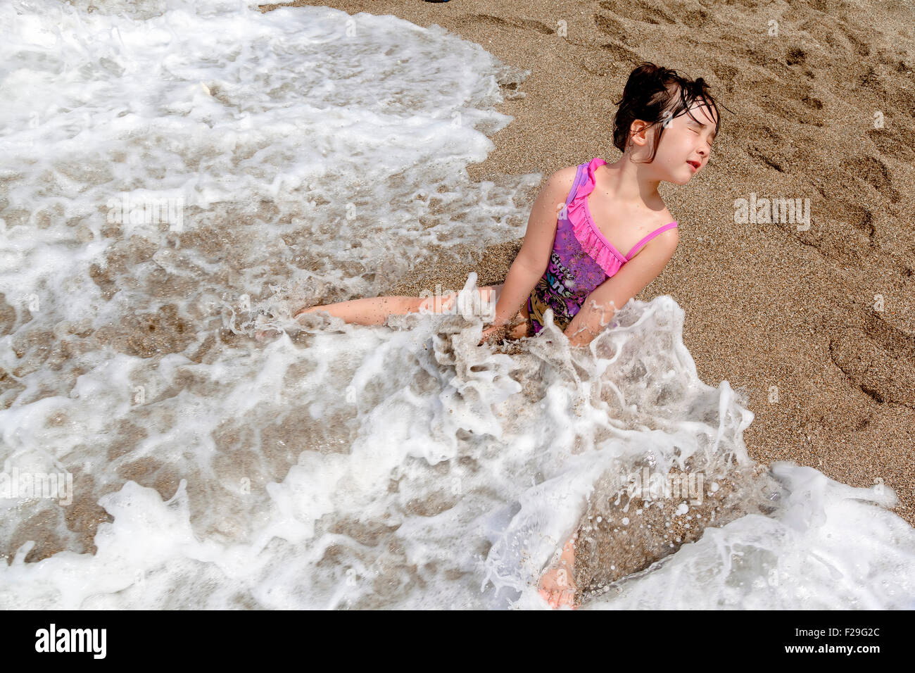 Kinder spielen im Wasser mit den Wellen am Strand Stockfoto