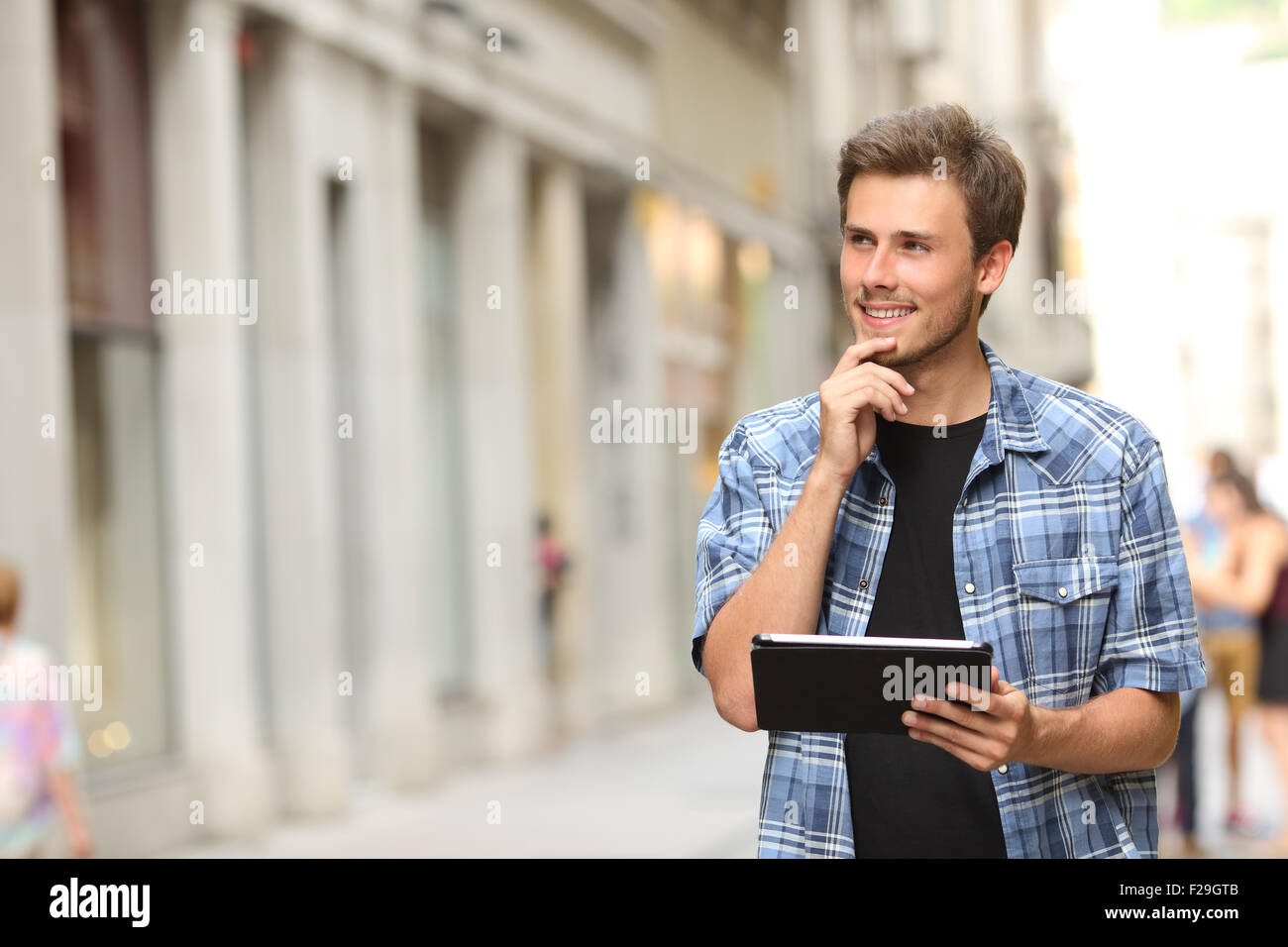 Glücklicher Mann hält eine Tablette und das Denken in der Straße Stockfoto