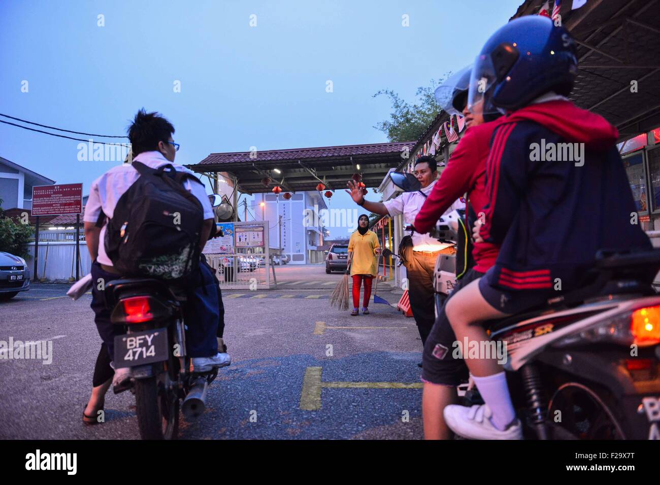 Cheras, Malaysia. 15. Sep, 2015. Ein Angestellter einer Schule Gesten, Patriarchen Motorradfahren mit ihren Kindern über der Schule der Tages-Schliessung in Cheras Selangor, Malaysia, 15. September 2015 zu informieren. Schulen in Malaysias Hauptstadt und mehrere Staaten haben gesagt, inmitten der sich verschlechternden Dunst aus dem benachbarten Indonesien am Dienstag geschlossen. © Chong Voon Chung/Xinhua/Alamy Live-Nachrichten Stockfoto