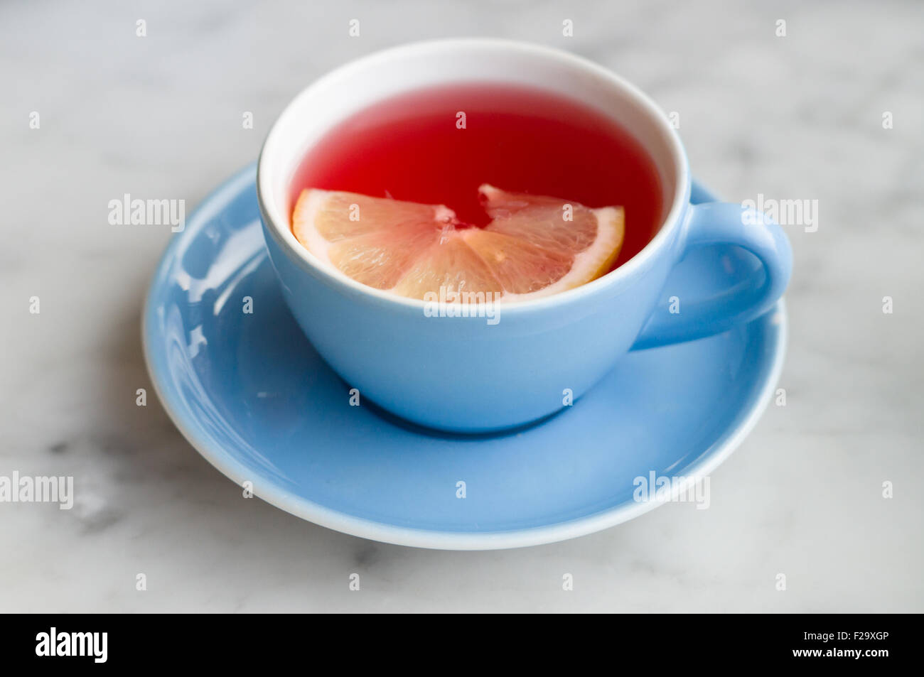 Roter Früchtetee mit Zitronenscheibe in blauen Tasse Stockfoto