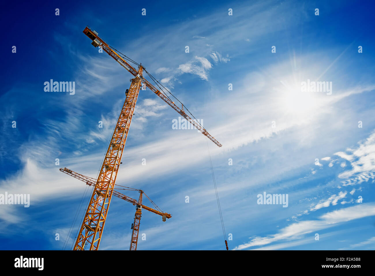 Zwei gelbe Industriekrane arbeitet auf Baustelle gegen blauen Himmel Stockfoto