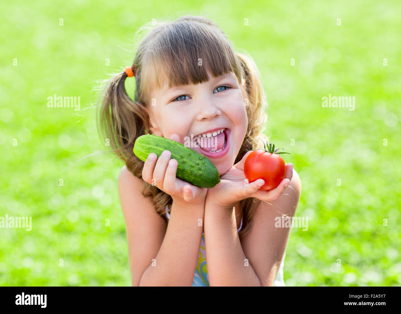 glückliches Kind leihweise Rasen mit gesundes Gemüse in ihren Händen Stockfoto