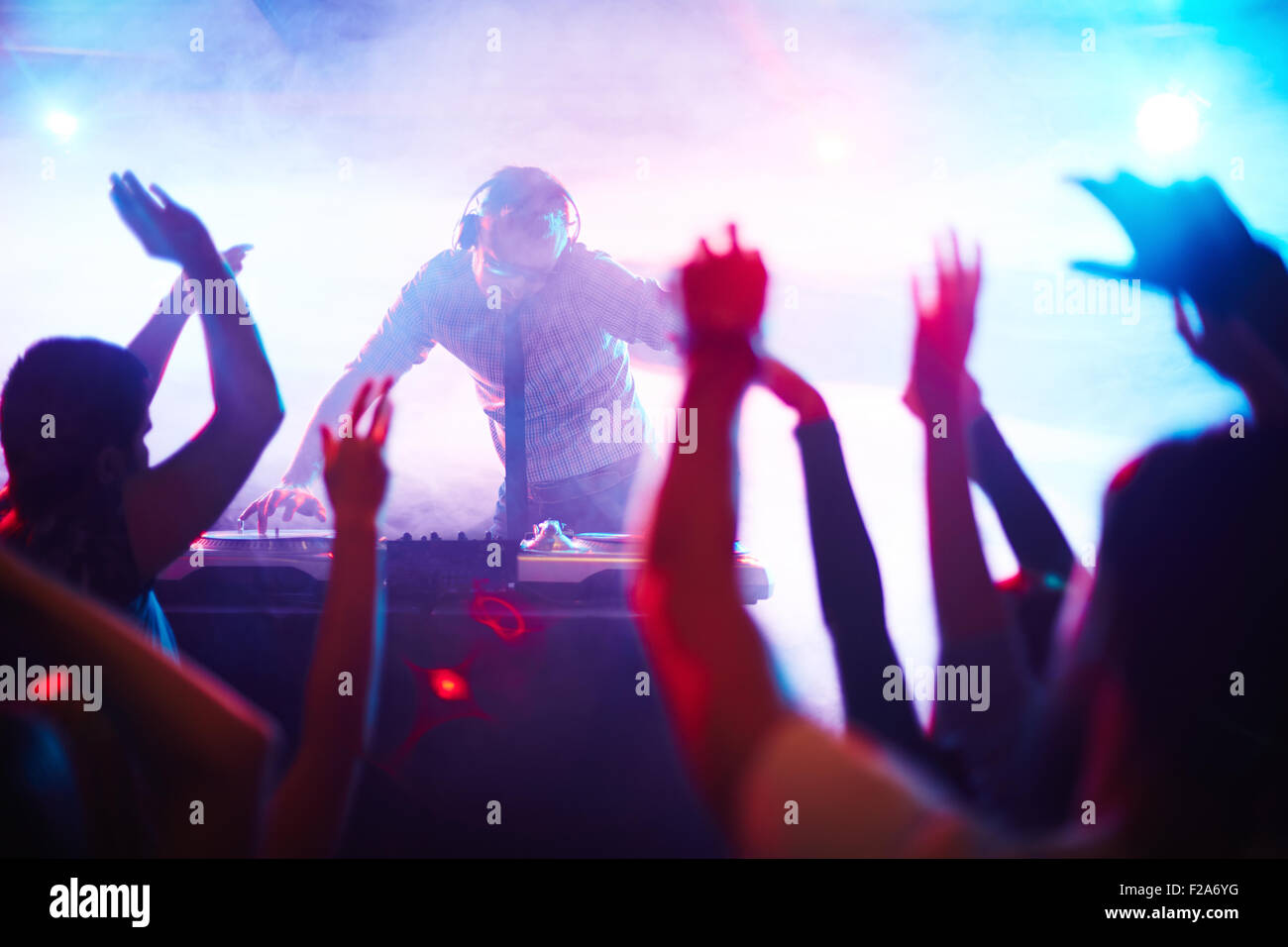 Energetische Deejay tatenlos Plattenspieler vor tanzenden Menschenmenge Stockfoto