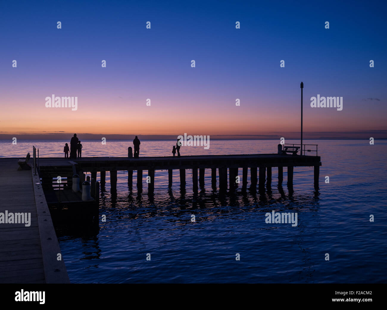 Silhouetten von Menschen stehen auf einem Pier bei Sonnenuntergang, Victoria, Australien Stockfoto