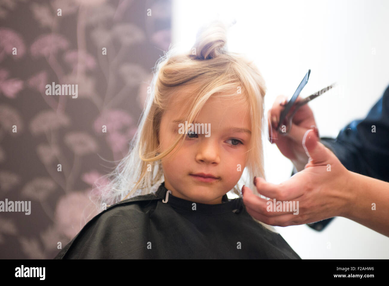 Weibliche Friseur schneiden und Bürsten Kind blondes Mädchen Haare im Friseursalon Stockfoto