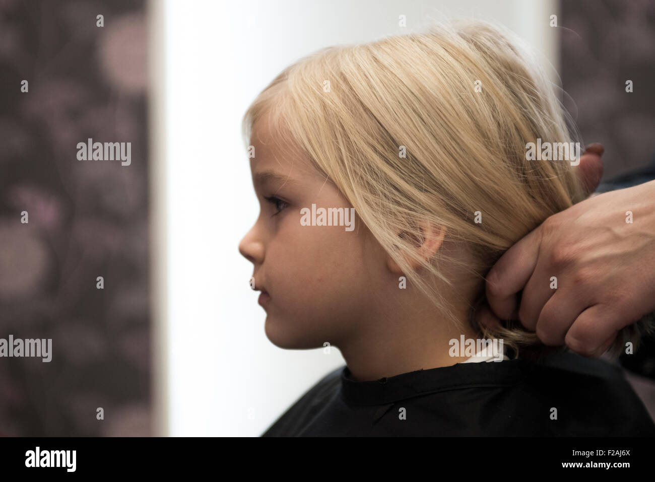 Weibliche Friseur schneiden und Bürsten Kind blondes Mädchen Haare im Friseursalon Stockfoto