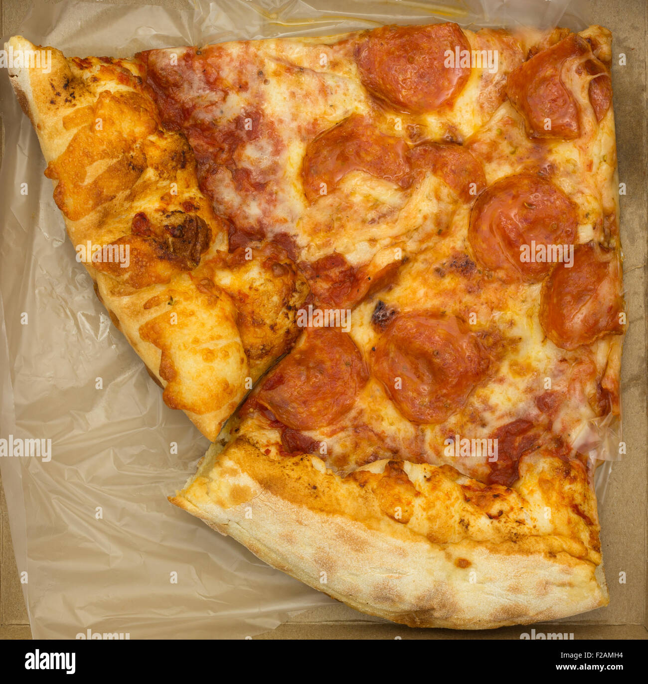 Draufsicht auf zwei Scheiben Salami Pizza in einem kleinen Karton. Stockfoto