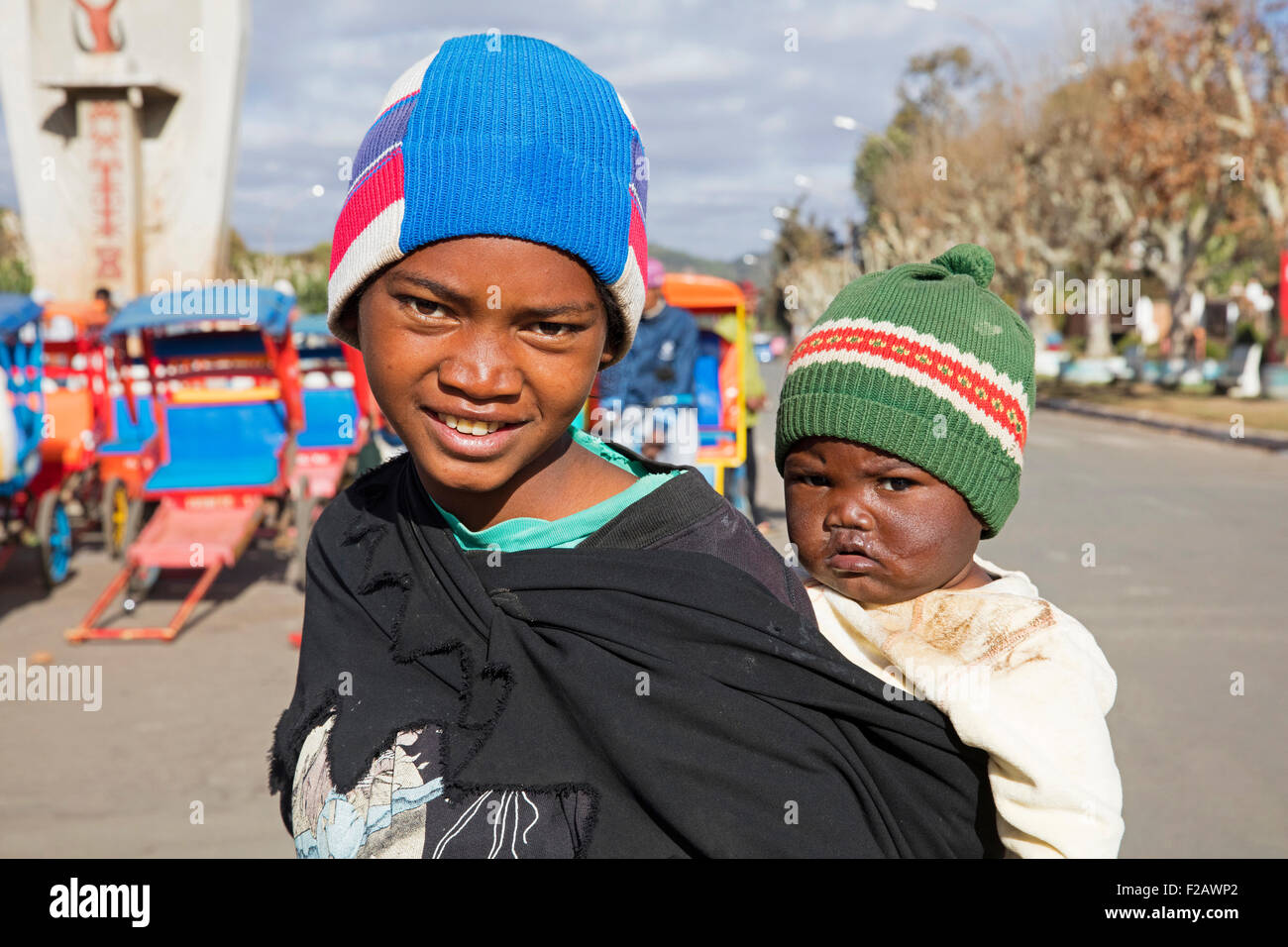 Madagassische Mädchen mit Kind auf dem Rücken in die Stadt Antsirabe, Vakinankaratra, Madagaskar, Südostafrika Stockfoto