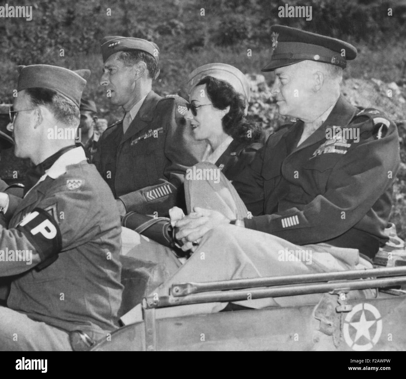 Kay Summersby sitzt zwischen Generäle Eisenhower und Mark Clark in einem Jeep. Sie waren in Deutschland, vorbei an den Ruinen von Hitlers Berchtesgaden Rückzug. Im Vordergrund ist Sitz Staff Sgt Harled Berg. 1945. Detail. (CSU 2015 11 1721) Stockfoto