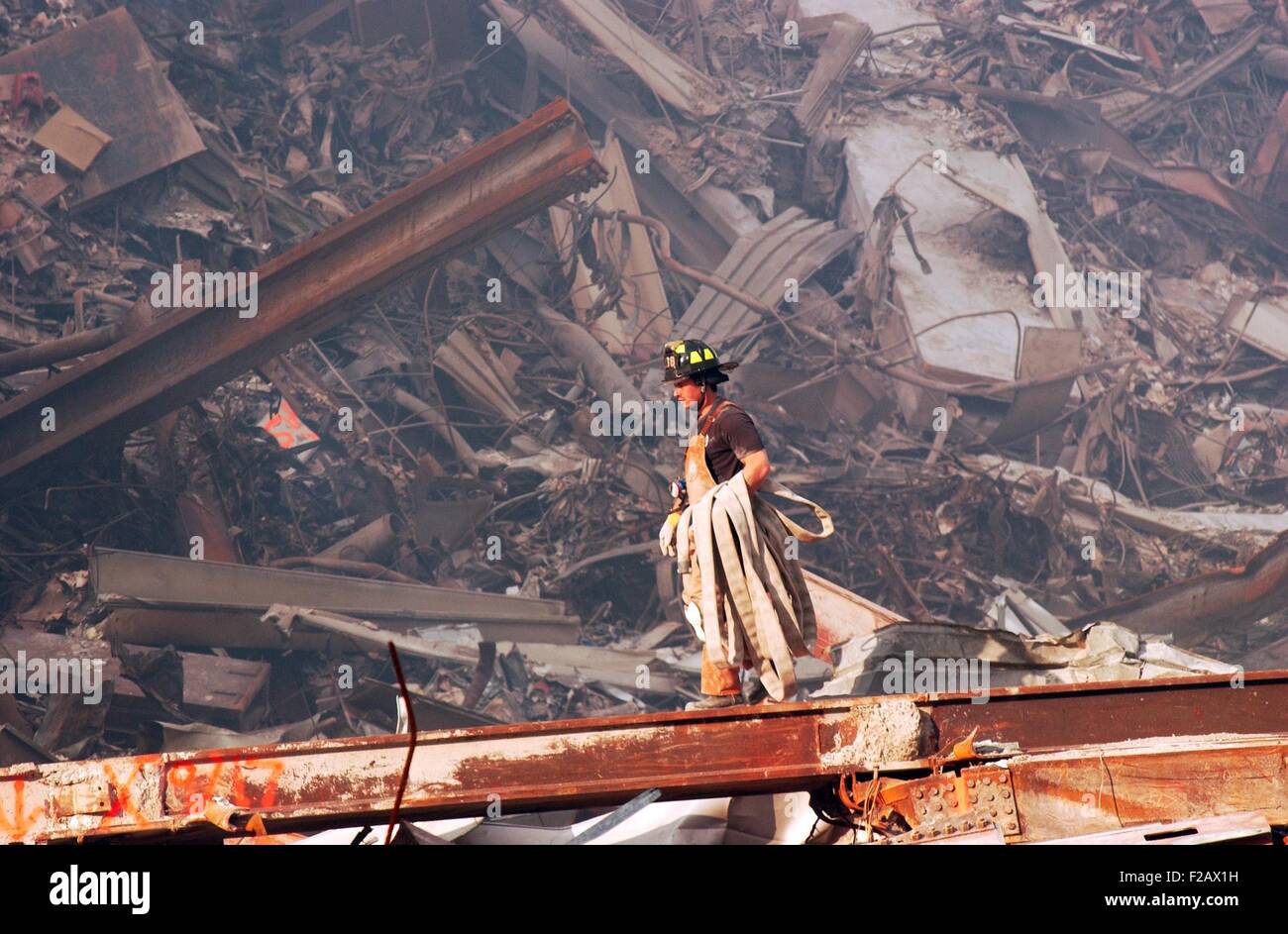 New York City Feuerwehrmann trägt ein Feuerwehrschlauch über schwelenden Bränden und Trümmer am Ground Zero, 18. September 2001. World Trade Center in New York City, nach dem 11. September 2001 Terroranschläge. (BSLOC 2015 2 97) Stockfoto