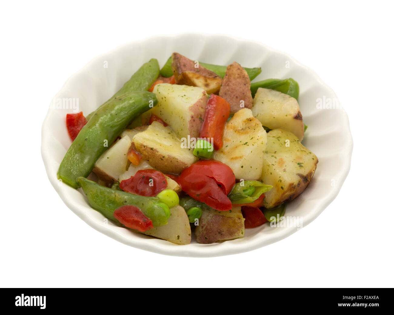 Eine Schüssel mit gerösteten Kartoffeln, Zuckerschoten und Paprika in einer Knoblauchsauce, isoliert auf einem weißen Hintergrund. Stockfoto