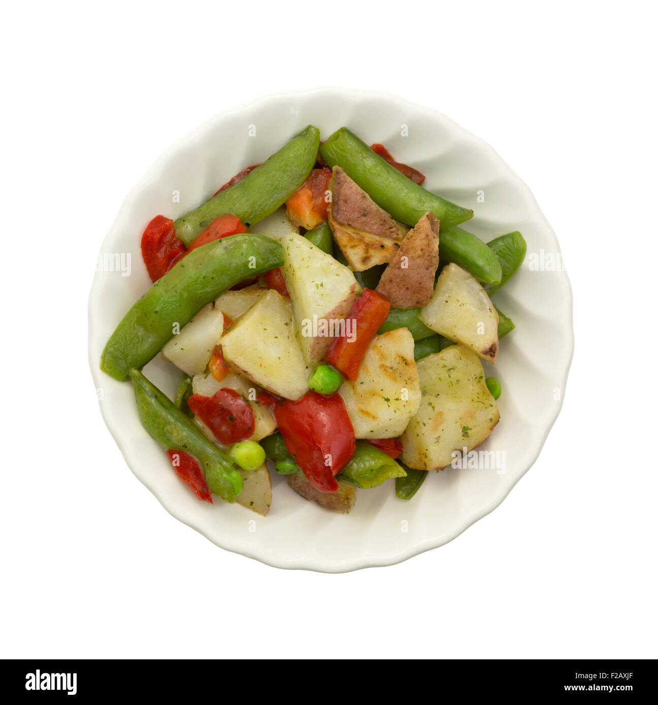 Draufsicht auf eine Schüssel mit gerösteten Kartoffeln, Zuckerschoten und Paprika in einer Knoblauchsauce, isoliert auf einem weißen Hintergrund. Stockfoto