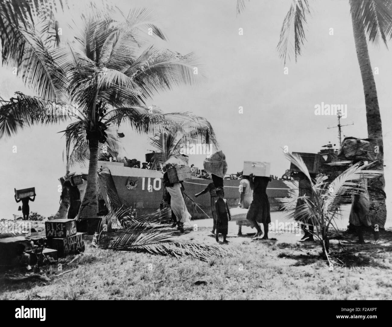 Menschen des Bikini-Atolls tragen ihr Hab und gut nach unten zum Boot. 40 Familien wanderten "vorübergehend" zu Rongerik-Atoll am 7. März 1946. Ihre Verdrängung war dauerhaft, weil die Atomexplosion BAKER und nach Tests, bestrahlt die Bikini-Insel, so dass es unbewohnbar. 23 Nuklearsprengsätze detonierten in der Bikini-Nähe zwischen 1946 und 1958 an sieben Teststellen. (BSLOC 2015 2 11) Stockfoto