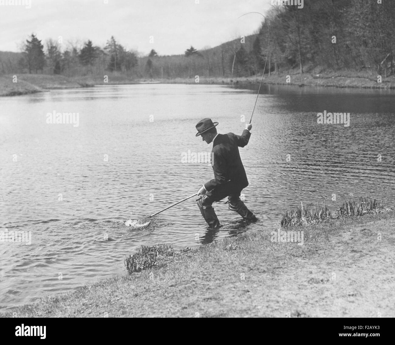 Präsident Calvin Coolidge mit einer Rute Angeln und net in einem Teich. Unbekannten Ort. Ca. 1925-28. (CSU 2015 9 781) Stockfoto