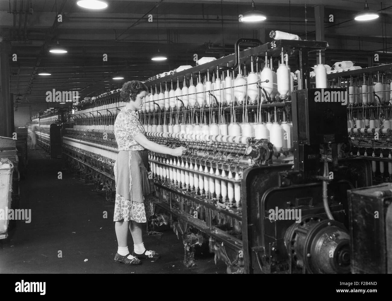 Frau stehend auf der langen Reihe von Spulen in einer Textilfabrik. Millville, N.J. 1936. Foto von Lewis Hine. -(BSLOC 2015 1 172) Stockfoto