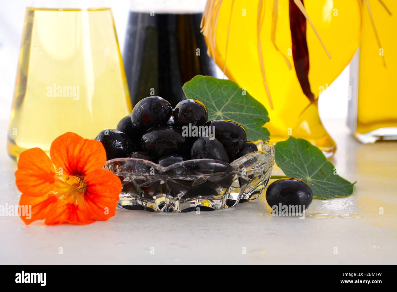 Salat-Dressing mit Essig auf weißer Holztisch, Closeup auf Oliven, Öle und Oliven. Stockfoto