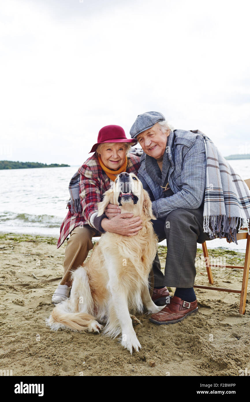 Pensionierter Mann und Frau und ihr Haustier entspannen am Meer Stockfoto