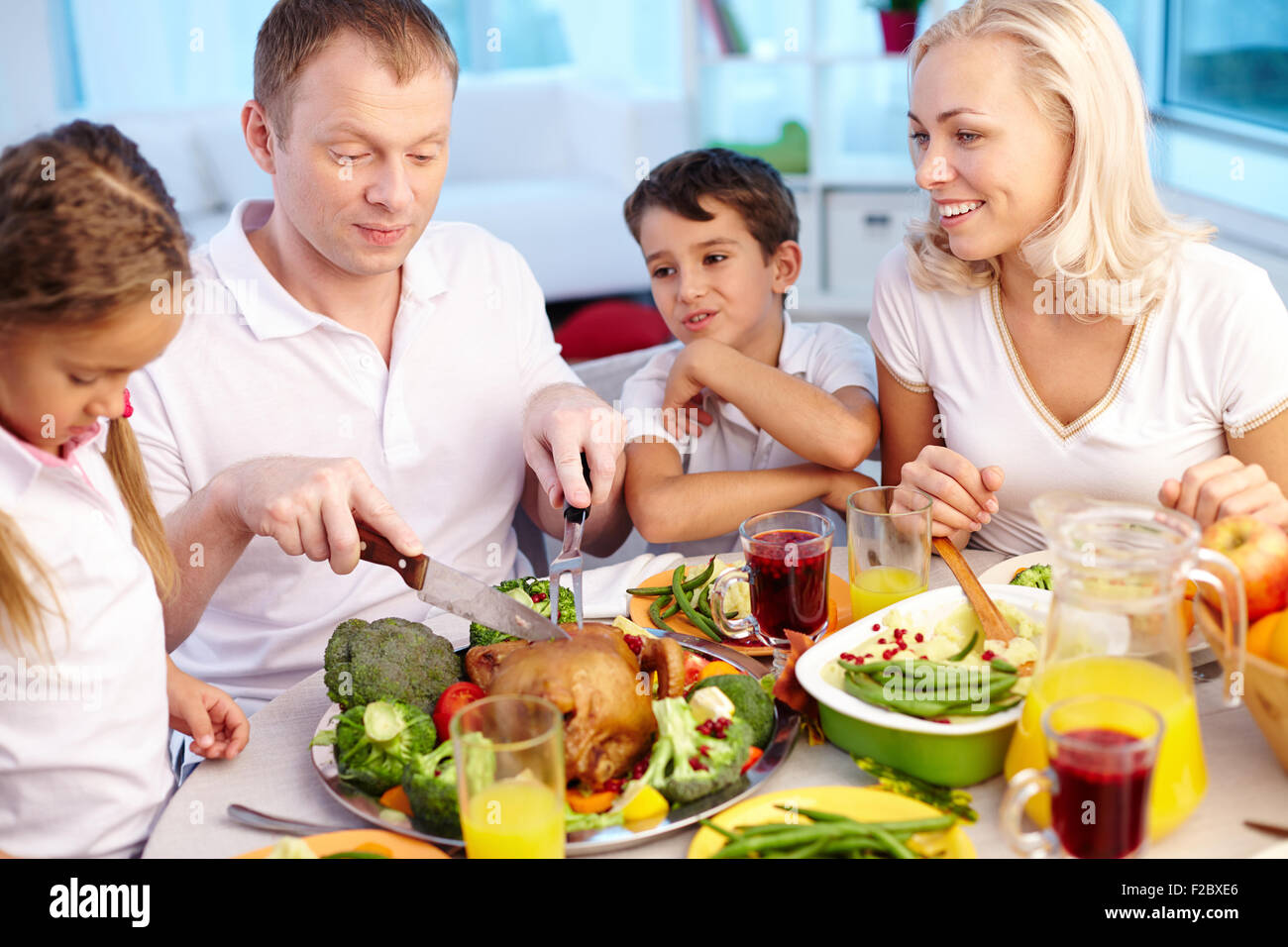 Glückliche junge Familie sitzen festlich gedeckten Tisch und traditionellen Thanksgiving Essen Stockfoto