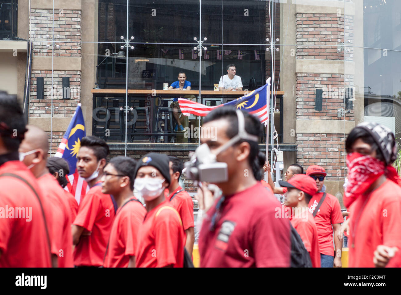 Kuala Lumpur, Malaysia. 16. Sep, 2015. Kunden in einem Coffee-Shop-Uhr als regierungsnahe red Shirt Demonstranten nehmen Teil an einer Demonstration in Kuala Lumpur, Malaysia, Mittwoch, 16. September 2015. Tausende von pro-malaiischen Demonstranten gingen auf die Straße von Kuala Lumpur am Mittwoch in einer Kundgebung als Förderung der malaiischen Vorherrschaft in der multi-ethnischen Nation gesehen. Hochrangige politische Vertreter und Oppositionsparteien geäußerten Bedenken der Rallye rassische Spannungen gleichzeitig entflammen könnte als Premierminister Najib Razak unter intensivem Druck über einen angeblichen Korruptionsaffäre zurücktreten wird. © Asia Datei/Alamy Live Ne Stockfoto