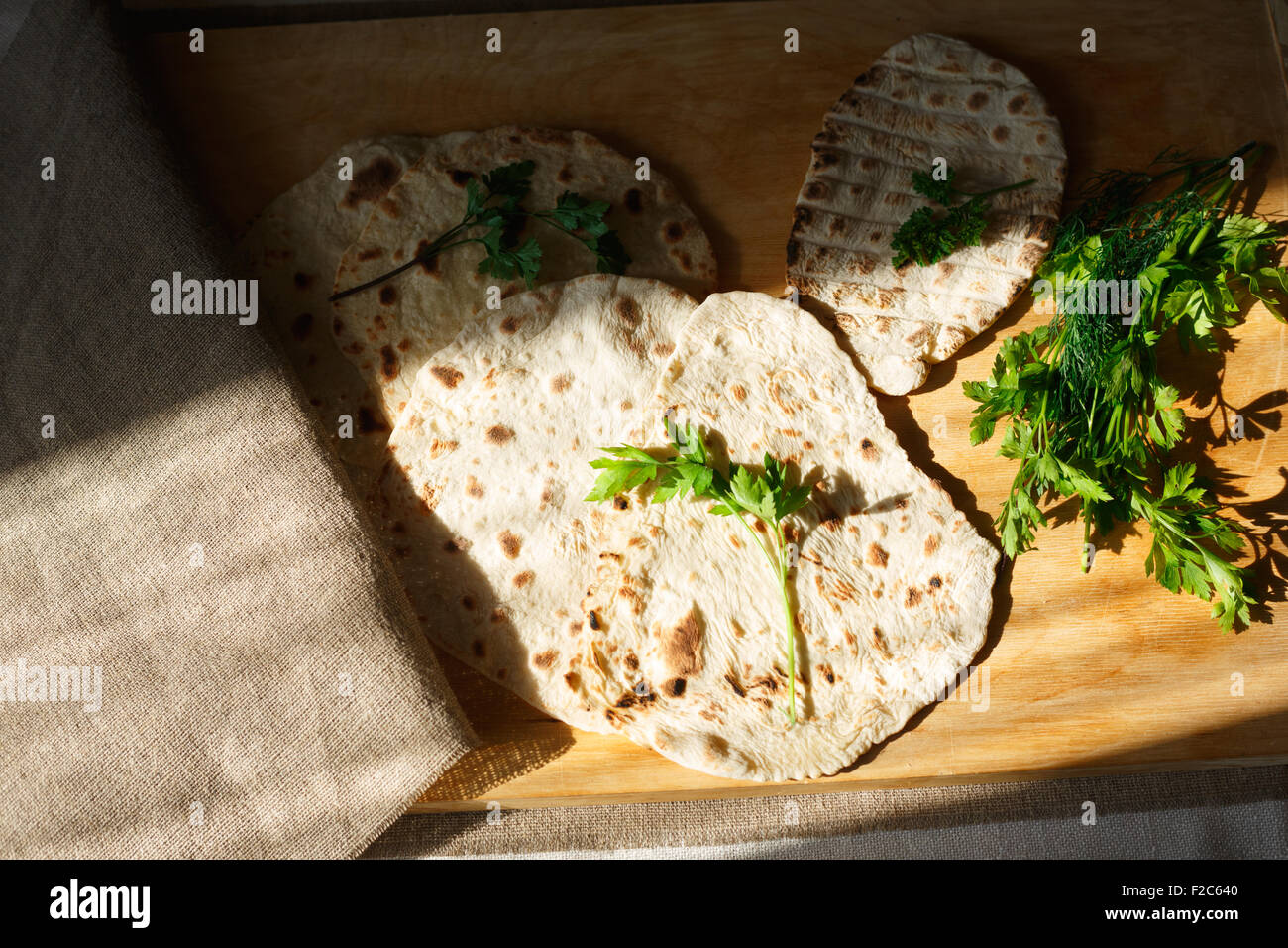 Indisches Naan Brot auf Holztisch neben grünen Stockfoto