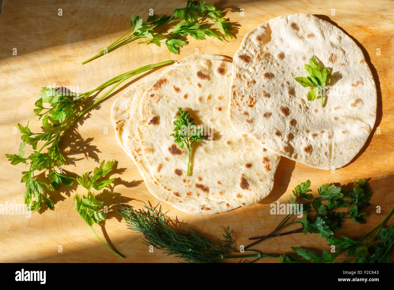 Indisches Naan Brot auf Holztisch neben grünen Stockfoto