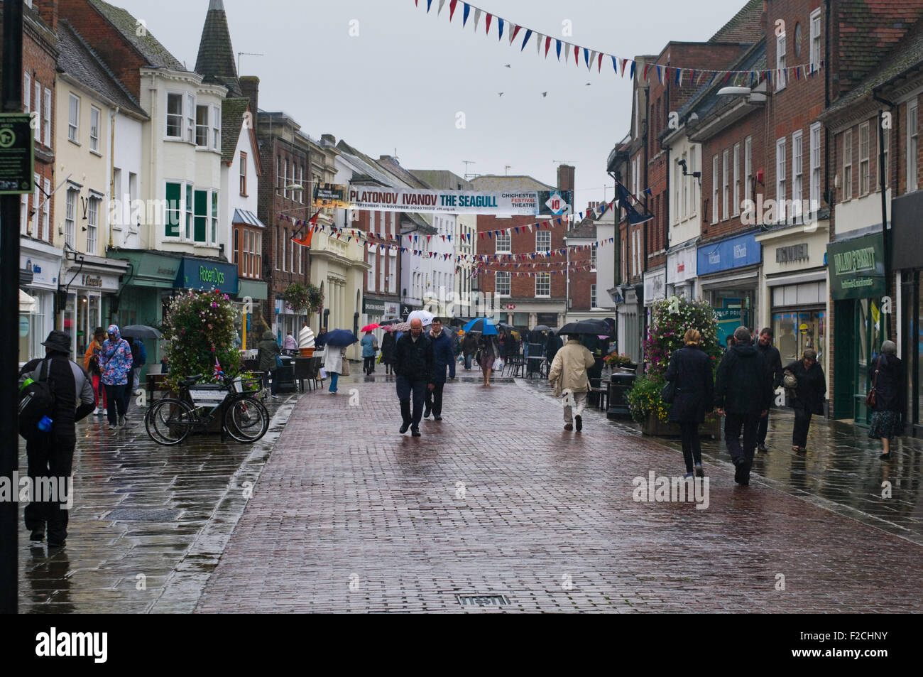 Nordstraße, Chichester, West Sussex, England. Die Menschen gehen mit  Sonnenschirmen an einem regnerischen Tag Stockfotografie - Alamy