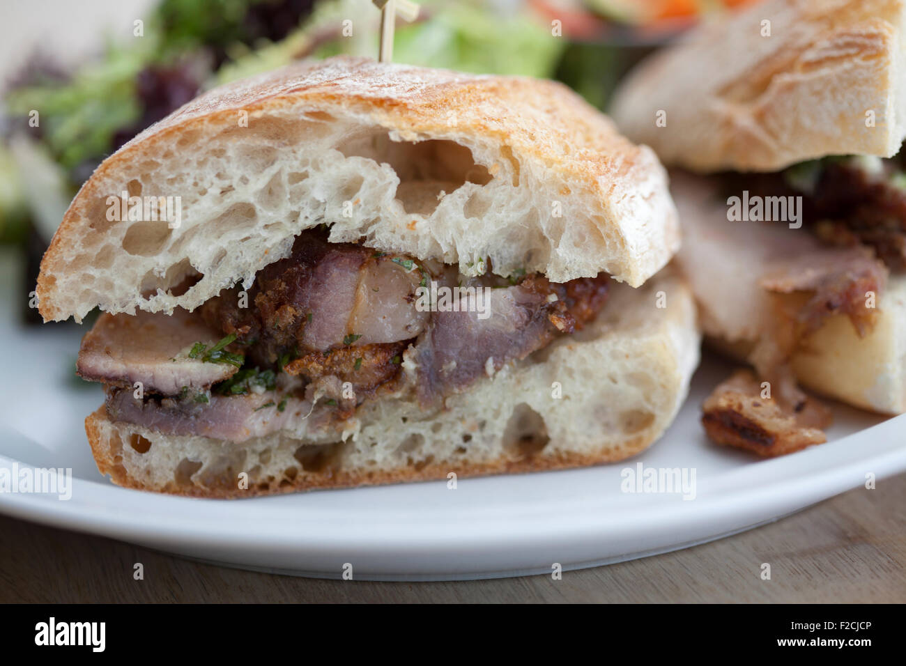 Seitenansicht der Porchetta Sandwich mit Salat auf weißen Teller Stockfoto